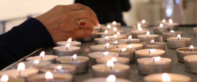 Frau steckt Kerzen in der Kirche an