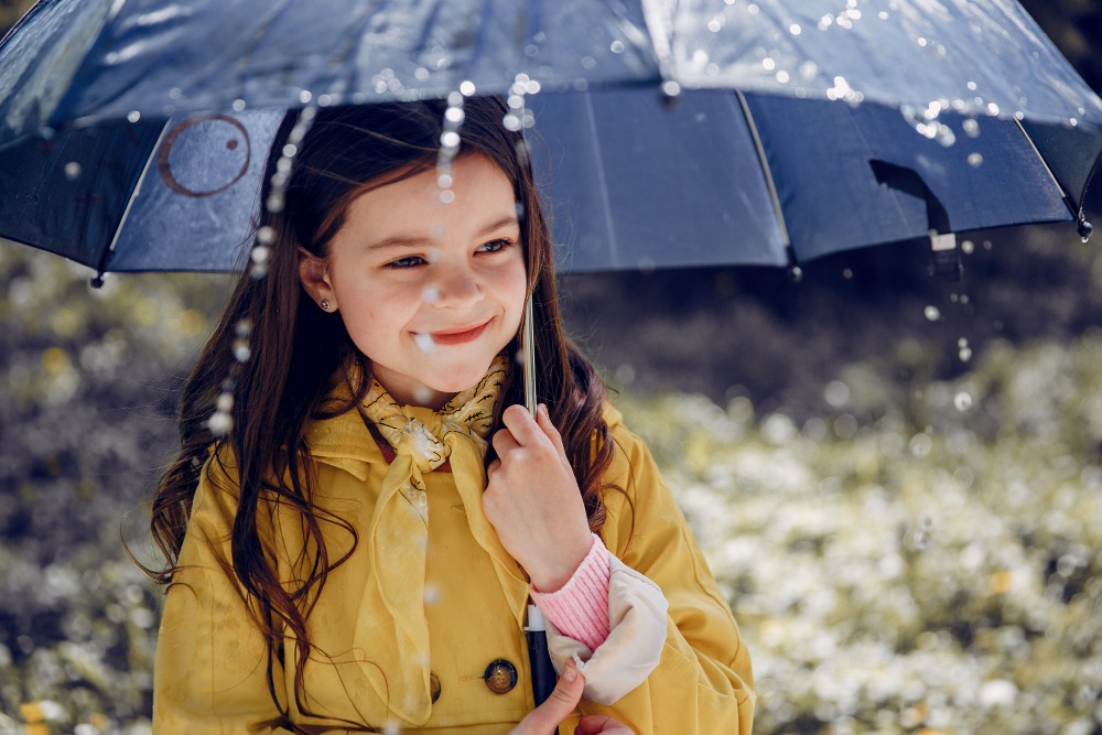 Ein lächelndes Kind mit Schirm bei Regenwetter