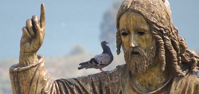 Eine Taube sitzt auf der Schulter einer Jesus-Statue.