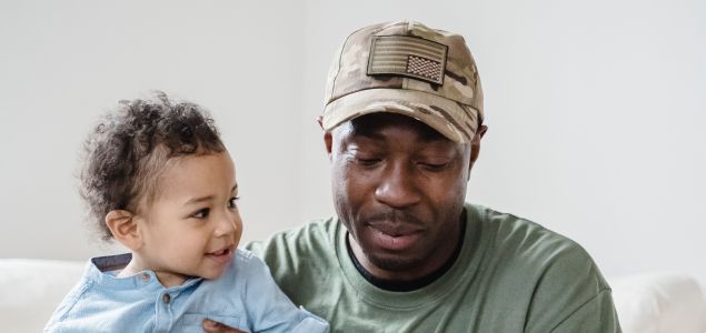 Ein müder Vater hält ein ein lächelndes Kind.