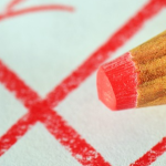 Ein roter Buntstift und ein Wahlkreuz