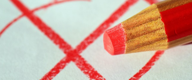 Ein roter Buntstift und ein Wahlkreuz