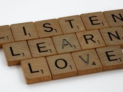 Spielsteine eines Scrabble-Spiels zeigen die englischen Worte: listen, learn, love.