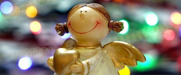 Ein Engel mit frohem Gesichtsausdruck vor weihnachtlicher Dekoration.