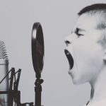 Ein Junge erhebt vor einem Mikrofon seine Stimme.