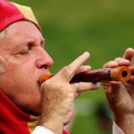 Ein Gaukler spielt auf einer Flöte.