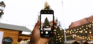 Mit einem Smartphone wird der Weihnachtsbaum auf einem Weihnachtsmarkt fotografiert.