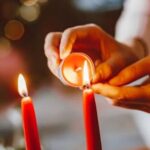 Eine Frau zündet Kerzen an einem Adventskranz an.