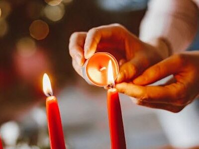 Eine Frau zündet Kerzen an einem Adventskranz an.