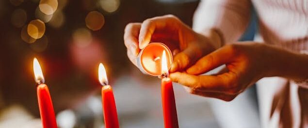 Eine Frau zündet Kerzen an einem Adventskranz an.