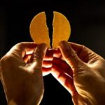 Zwei Hände halten eine gebrochene Hostie.