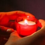 Eine Person hält eine Gebetskerze in einer Kirche in den Händen.