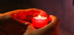 Eine Person hält eine Gebetskerze in einer Kirche in den Händen.
