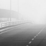 Eine Person läuft auf einer Brücke im Nebel.