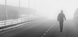 Eine Person läuft auf einer Brücke im Nebel.
