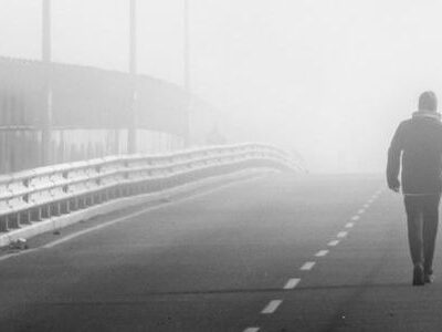 Eine Person läuft auf einer Brücke im Nebel.