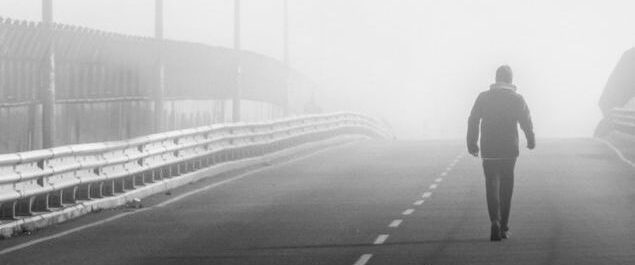 Eine Person läuft auf einer Brücke im Nebel.